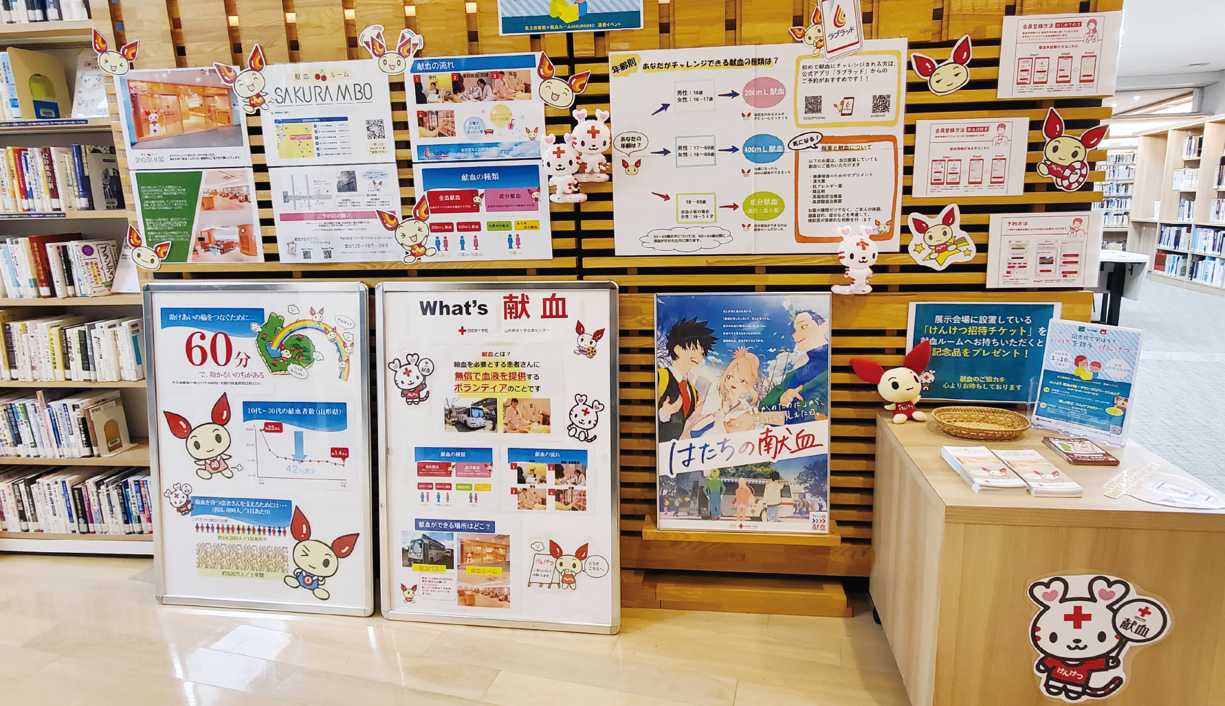 図書館の一角に設けられた展示スペース。スタッフが資料やパネルを運び込み、準備を進めます