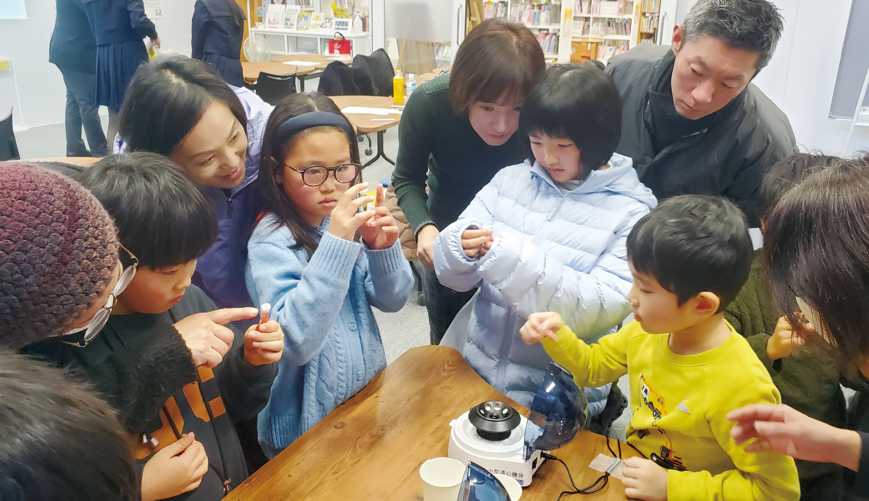 遠心分離機の体験に集まる子どもたち。変化していく様子を、親子でのぞき込むように見つめていました