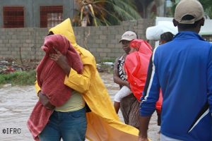 Cayes, southern Haiti, October 5, 2016. Hurricane Matthew has struck Haiti. Initial effects on the terrain and structures. Flooded streets. Broken trees. Houses destroyed. A family is moving towards a shelter centre.