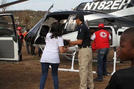 ヘリコプターで届けた医薬品を運び出すスタッフと赤十字ボランティア