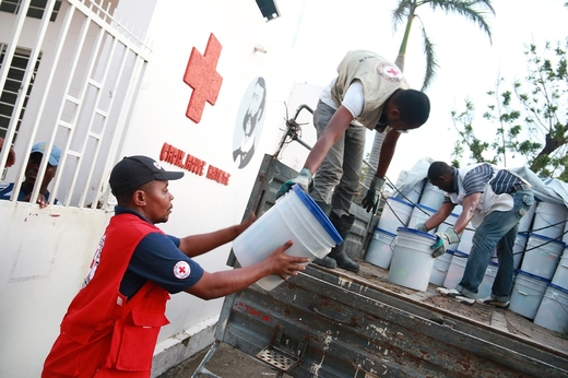 トラックで衛生用品を運び人びとに配る赤十字ボランティア