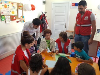 シリア難民のためのコミュニティセンターで折り鶴の折り方を教える笠岡さん（写真中央）©トルコ赤新月社