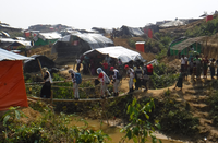 避難民の簡易テントが並ぶ中、竹の橋を渡る日赤医療チーム