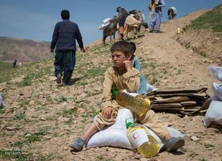 アフガニスタン赤新月社からの支援物資を受け取り、休息するこども