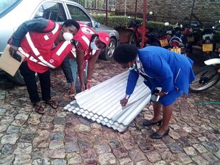 被害のあった家屋に屋根を配布するルワンダ赤のボランティア