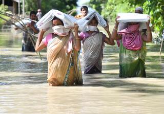 アッサム地方、道路が浸水している中で救援物資を受け取る地元住民