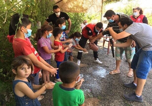 子どもたちに手洗いを教えるレバノン赤十字社のボランティアとスタッフ