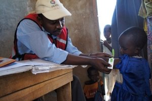 巡回診療で幼児の腕の太さを計測するスタッフ